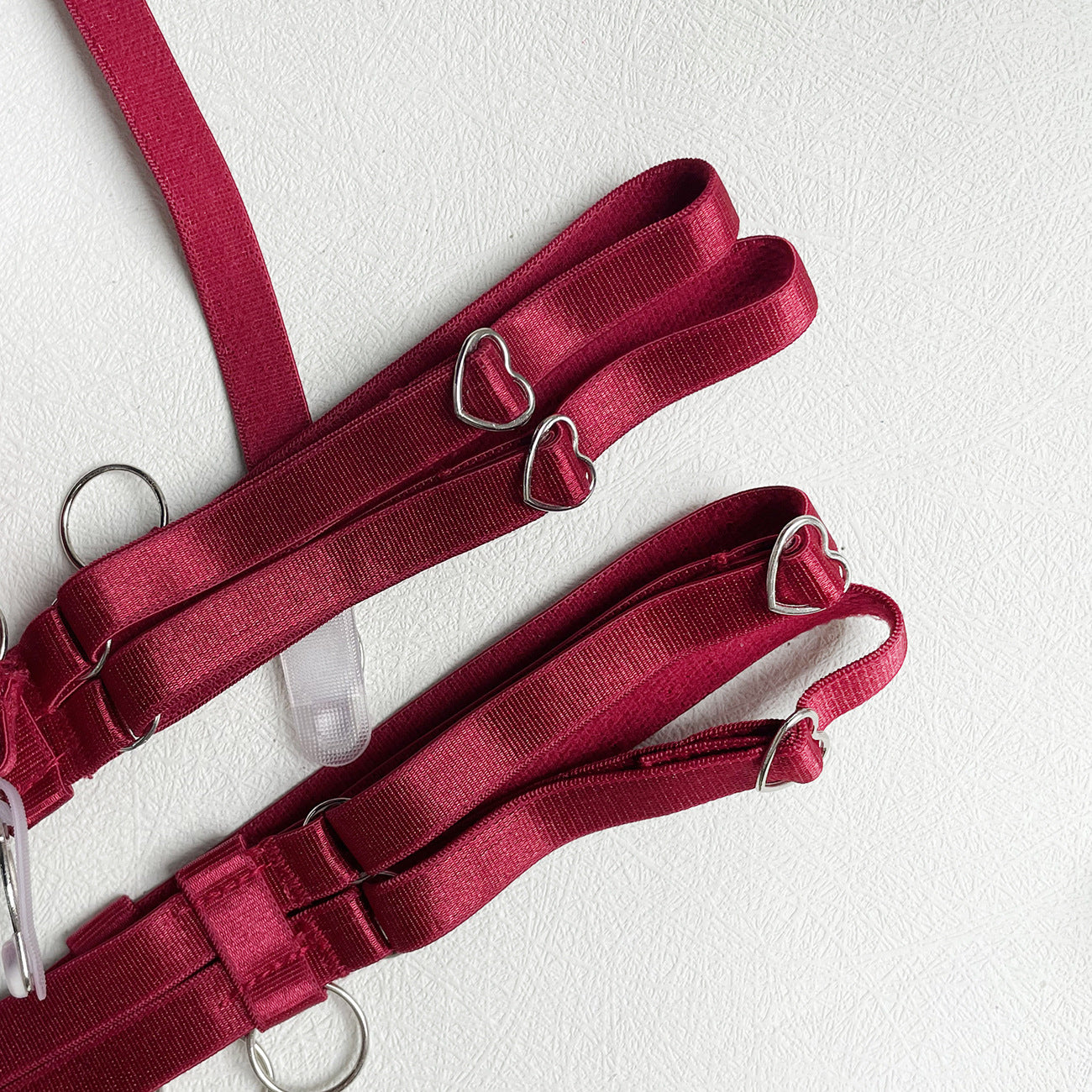 An intimate focus on the adjustable wine-red garter straps and heart-shaped rings, showcasing the disciplined symmetry of the Heartbound Flora design.