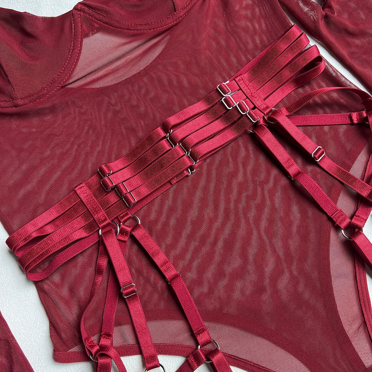 A detailed close-up of the adjustable silver-tone buckles and burgundy satin straps, highlighting the disciplined, industrial edge of the set.