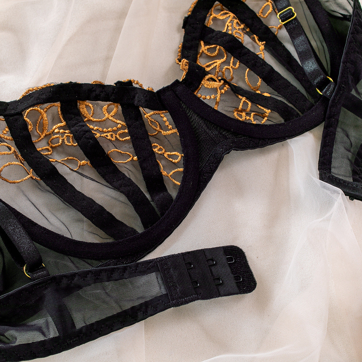 A detailed flat lay of bra showing the tactile quality of the golden knit embroidery and the premium mesh fabric. 