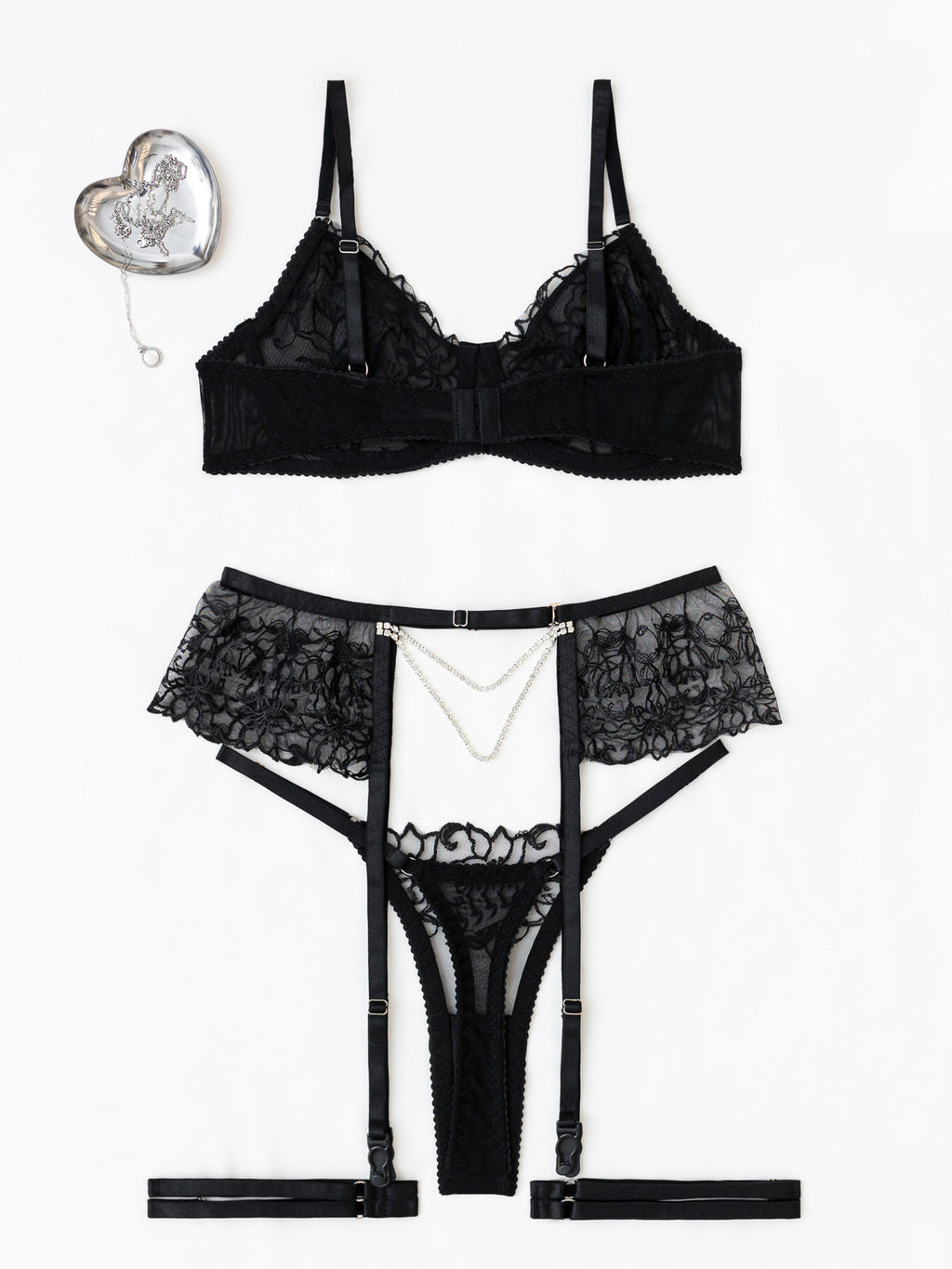 Rear-view studio flat lay of the black set on a white background, specifically showcasing the minimalist thong cut and pearl chain drape.