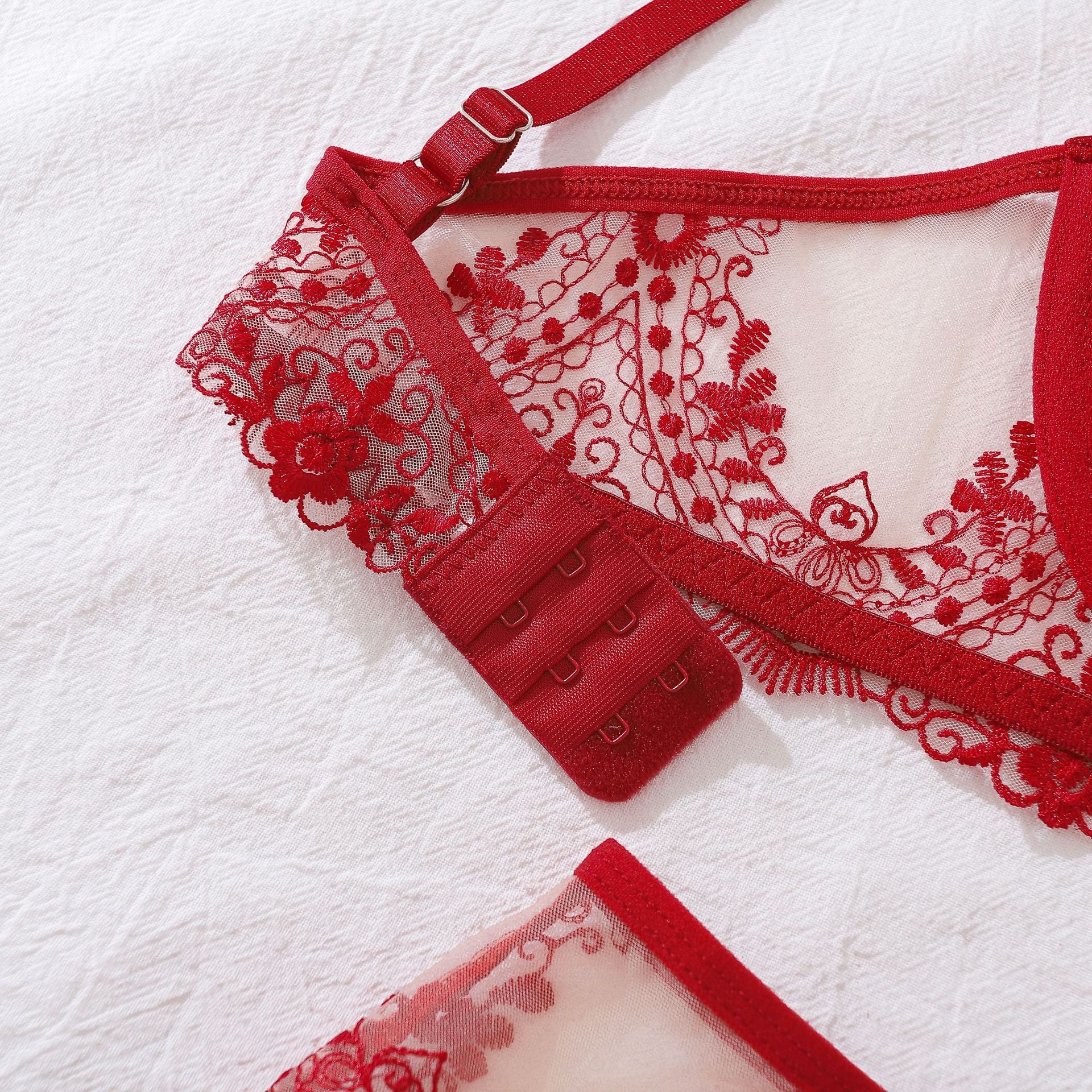 A macro flat lay focusing on the gold-tone sliders and rings against the red satin straps, capturing the luxurious, boutique-quality finishes of the set.