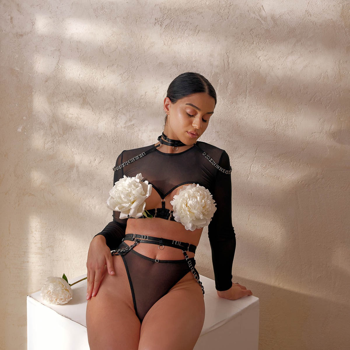 A seated editorial shot against a warm backdrop, showcasing the soft drape of the chains and the breathable mesh texture.