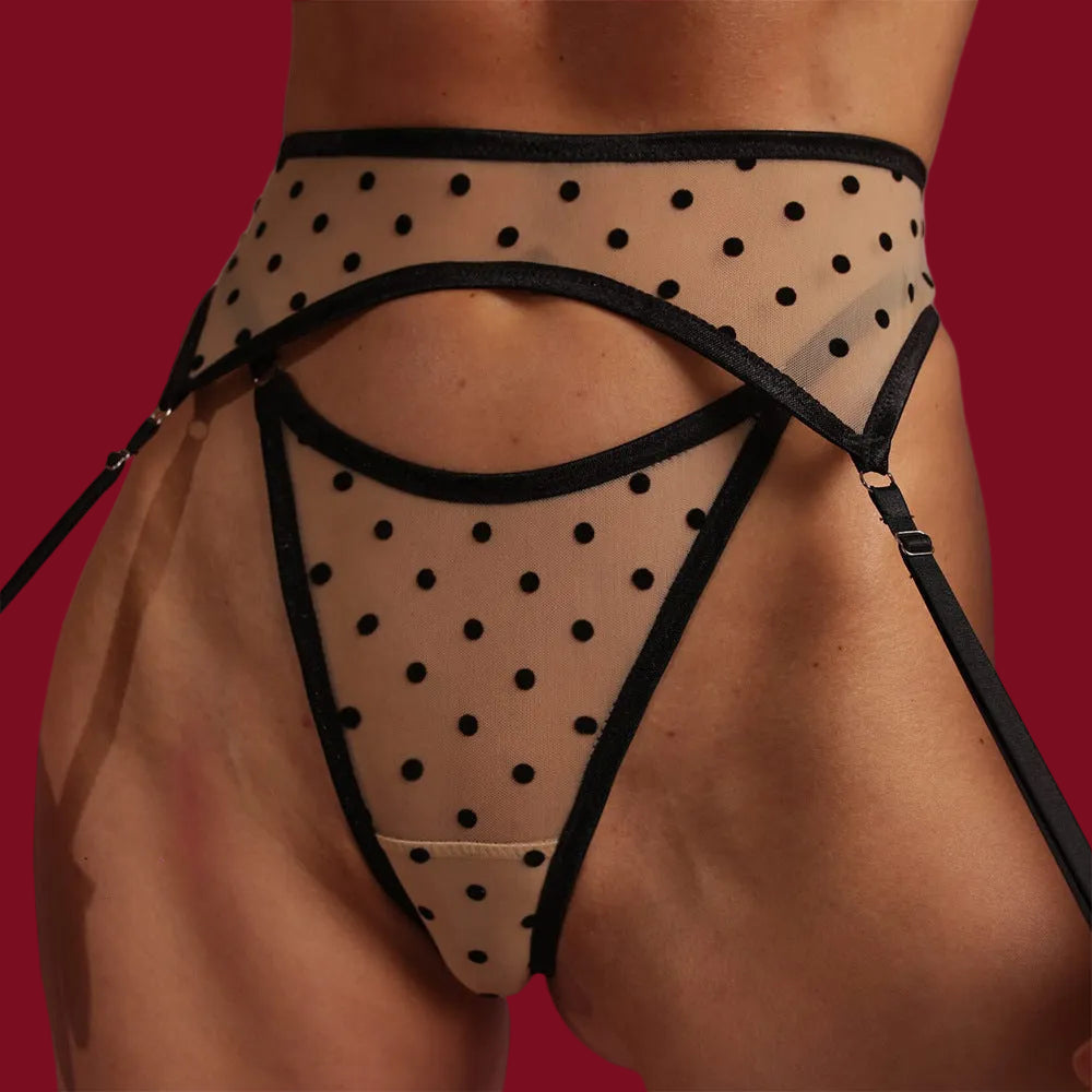 A detailed close-up of the polka dot garter belt and high-rise thong, showing the graphic black dots floating over sheer nude mesh.