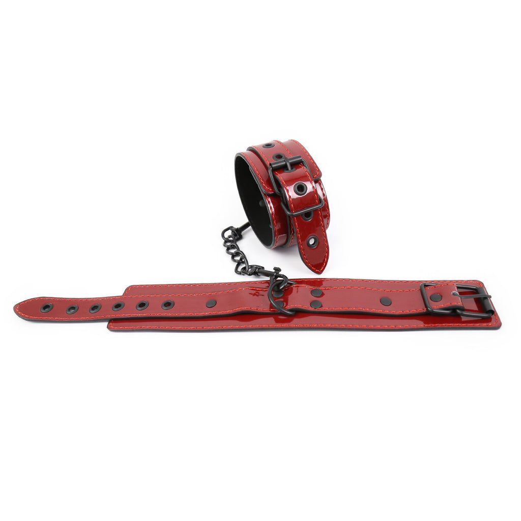 Pair of high-gloss red patent leather hand cuffs with reinforced black matte hardware and soft interior lining.