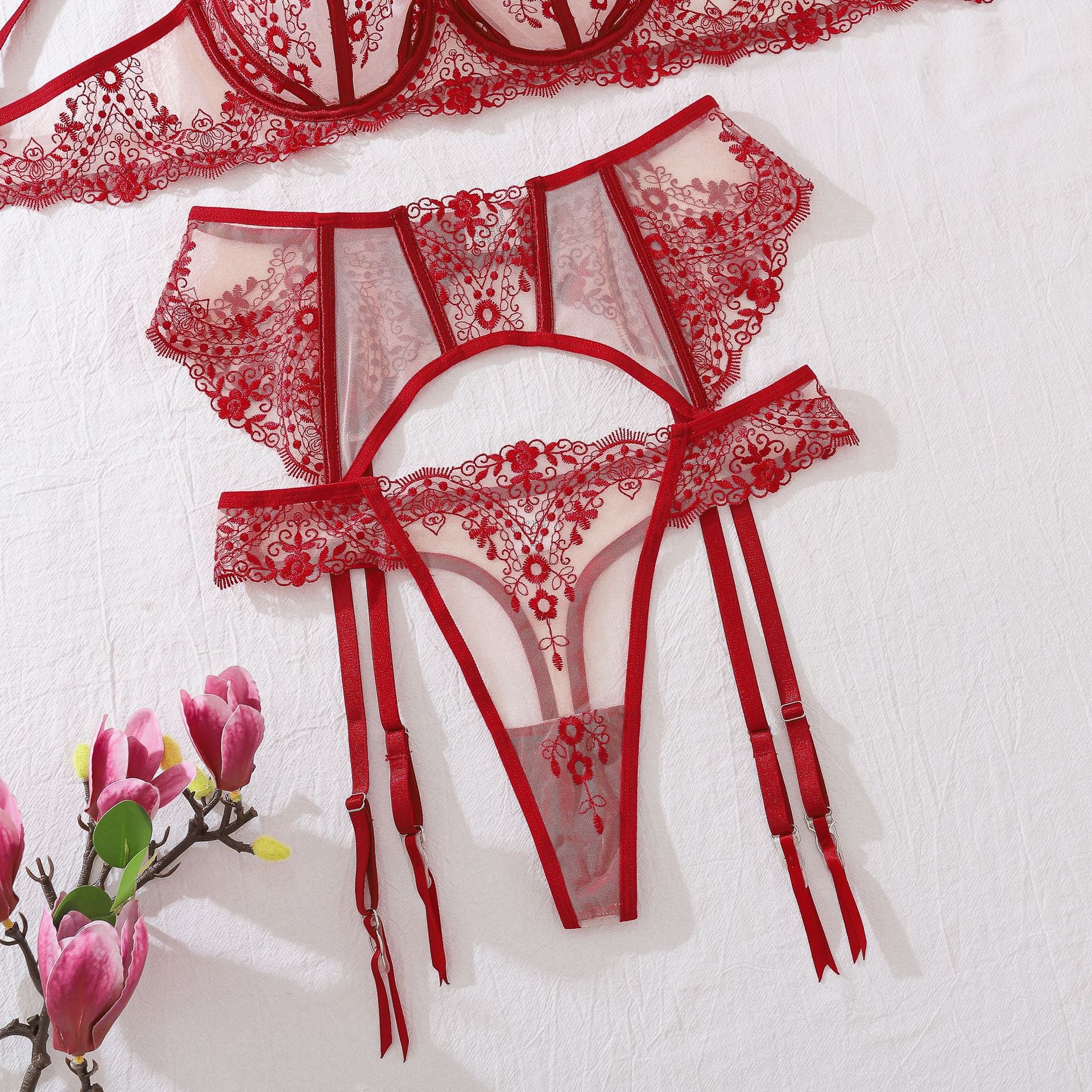 Detail view of the Midnight Muse garter belt. The flat lay emphasizes the floating floral panel and the contrast between the soft embroidery and the sharp, functional straps.