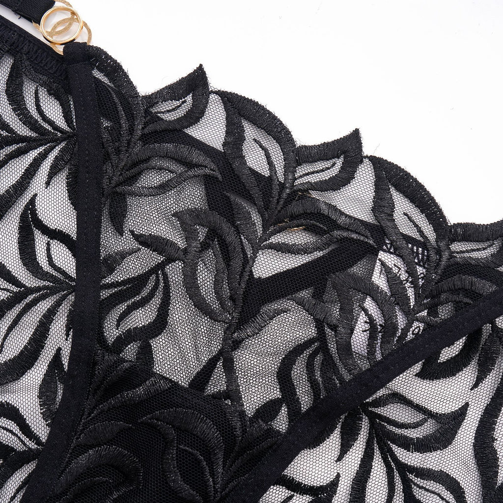 Macro shot of the fine botanical embroidery on high-clarity transparent mesh.