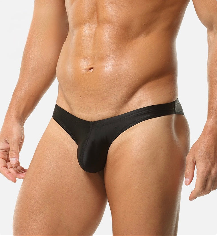 Athletic male model wearing classic black smooth nylon men’s brief with minimalist design.