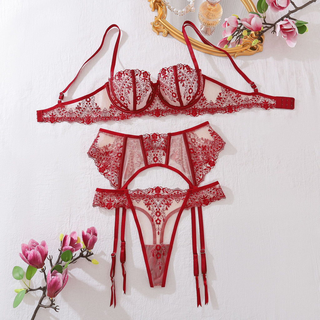 A complete front-view flat lay of the 3-piece set. The image showcases the symmetry of the floral embroidery and the architectural layout of the balcony bra, garter, and thong.