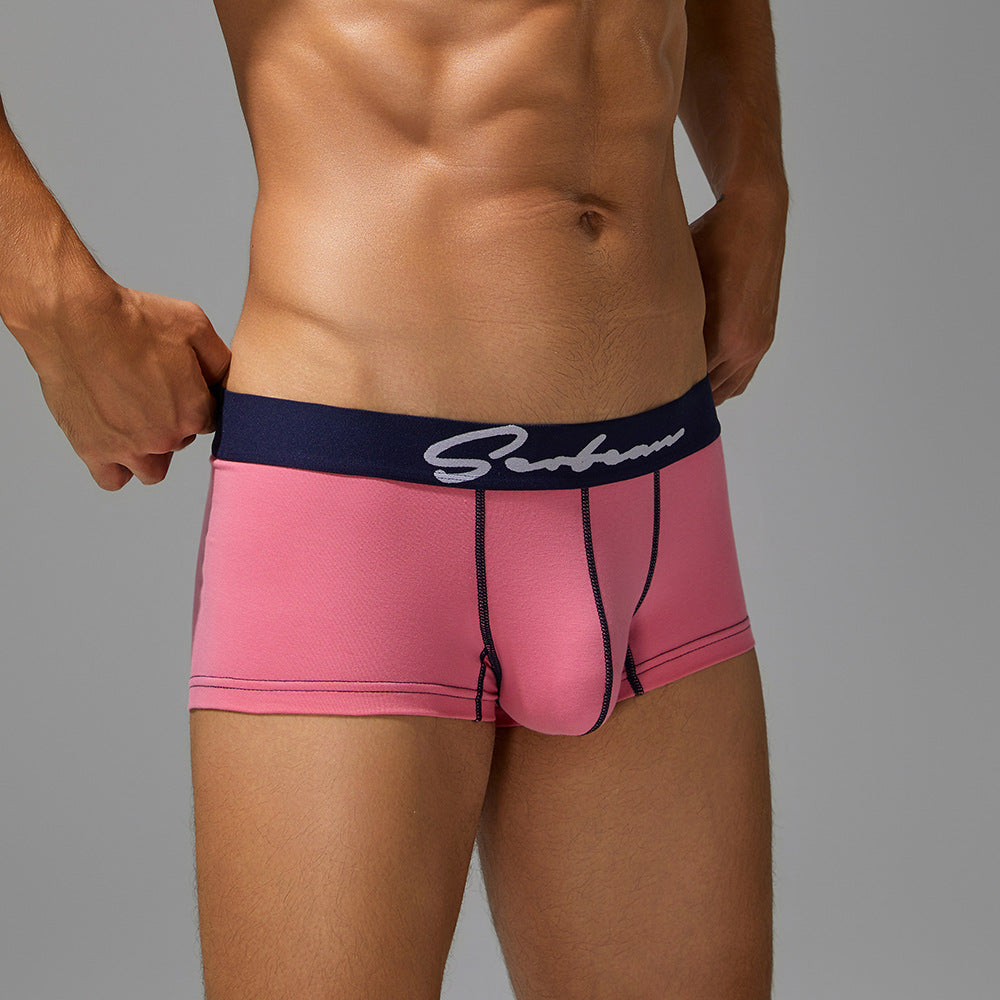 Side kinetic view of men's pink organic cotton trunks, highlighting the high-cut leg and comfortable navy elastic band.