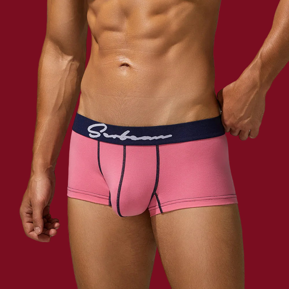 Angled view of pink organic cotton trunks on a male model, showcasing the ergonomic bridge pouch and smooth, matte texture.