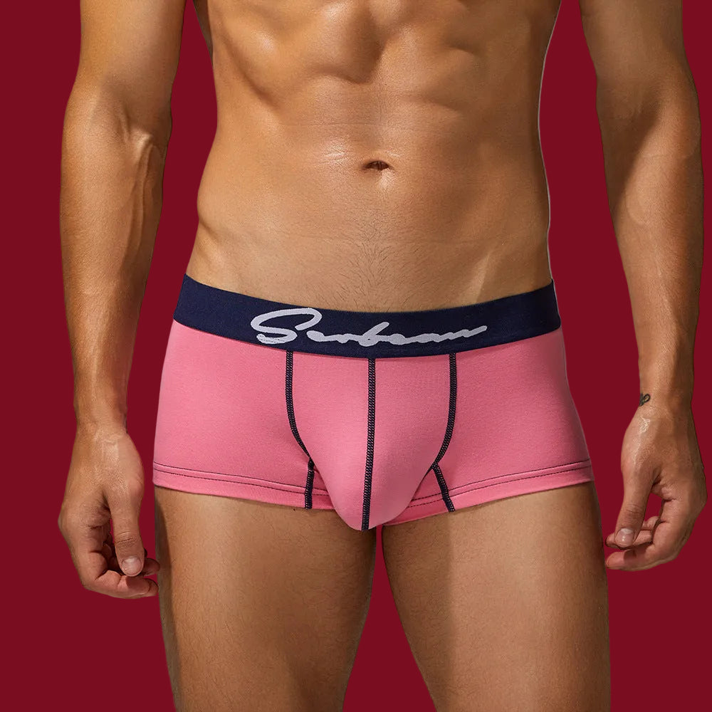 Front view of male athlete in pink organic cotton trunks with a navy contrast waistband for a smooth, breathable fit.